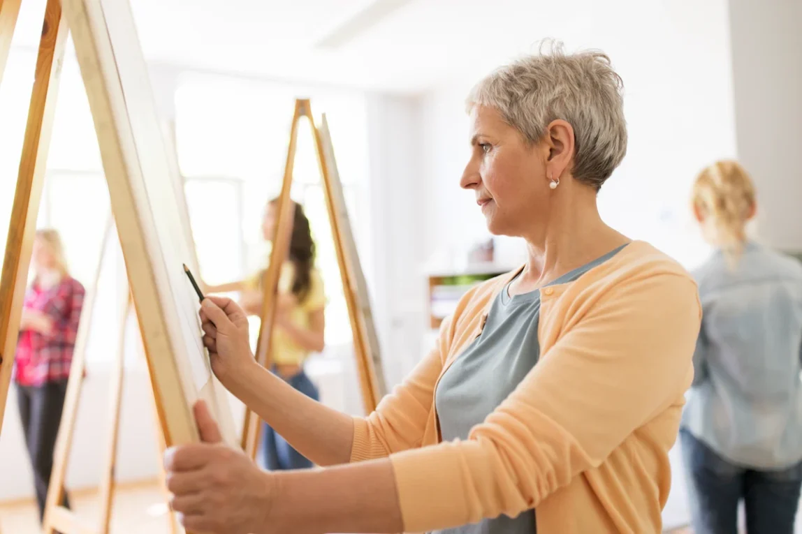 Senior woman drawing on easel